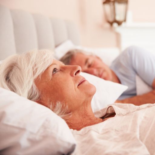older woman lying on back in bed awake can't roll over